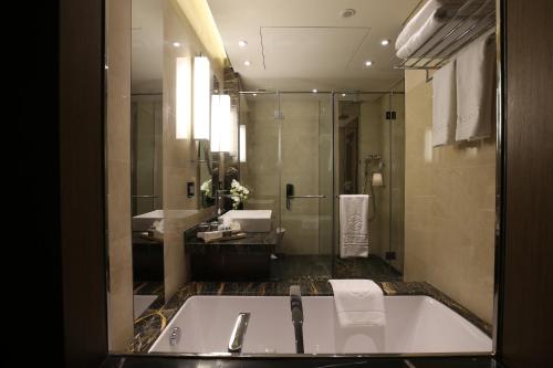 a bathroom with a tub and a sink and a shower at Lancaster Plaza Beirut in Beirut