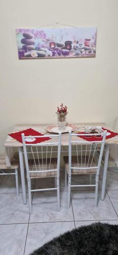 a white table with two chairs and a table and a painting at Angela's Apartment with beautiful balcony view in Agios Konstantinos Fthiotida