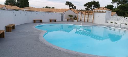 une grande piscine bleue entourée de bancs dans l'établissement Maison de vacances 4 personnes, à La Tranche-sur-Mer