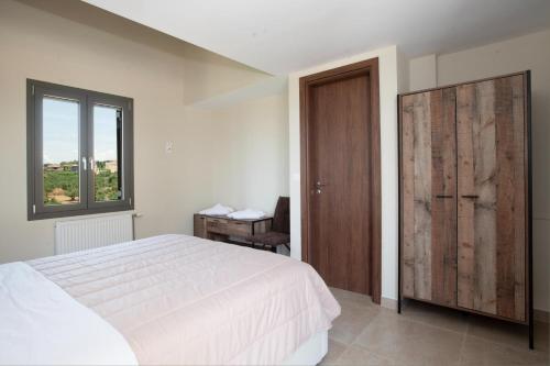 a bedroom with a white bed and a wooden door at Modone Villas in Peloponnese in Methoni