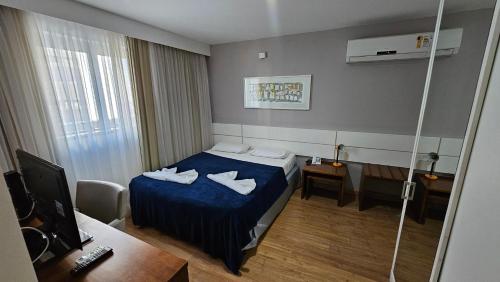 サルバドールにあるFLAT Salvador Business Corporationのベッドとデスクが備わるホテルルームです。