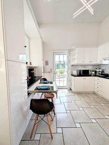 a white kitchen with a table and a chair at Ecoscape Luxury Villa Lamia in Lamía