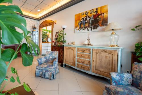 a living room with a wooden dresser and two chairs at Hotel Arillo in Noja