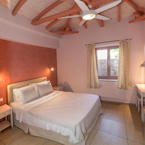 a bedroom with a white bed and a window at Athena's cottage Stoupa in Stoupa