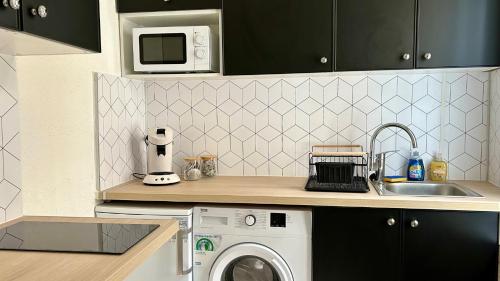 une cuisine avec un évier et une machine à laver dans l'établissement Le Mary, à Autun