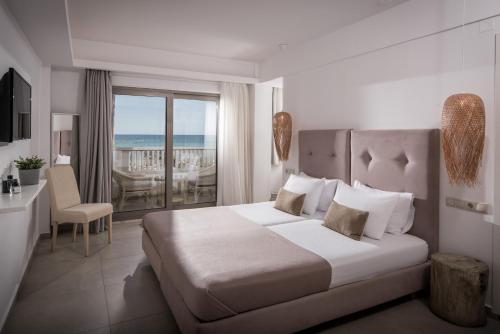 a bedroom with a bed and a balcony with the ocean at Soleil Rooms and Suites in Stalida
