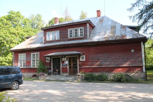 a red house with a car parked in front of it at Lindi kooli kohvik in Pärnu