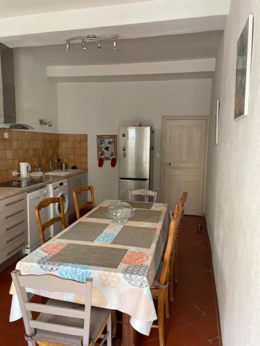 une cuisine avec une table, des chaises et un réfrigérateur dans l'établissement Maison de caractère rénovée Coggia, à Coggia