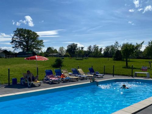un groupe de personnes assises sur des chaises dans une piscine dans l'établissement Les Fruits du Passau, à Saint-Désiré