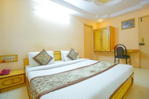a bedroom with a large bed and a chair at Hotel Upasana in Rajkot