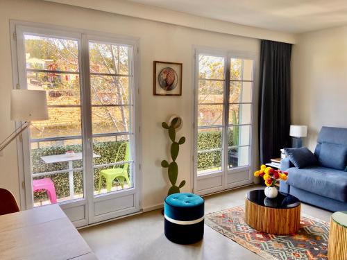 un salon avec un canapé bleu et des fenêtres dans l'établissement St Tropez T2 central, à Saint-Tropez