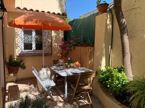 une table et des chaises avec un parasol sur une terrasse dans l'établissement Petit coin de paradis au cœur de Marseille, à Marseille
