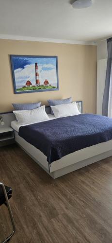 a bedroom with a bed with a lighthouse on the wall at Hotel Am Deich in Norddeich