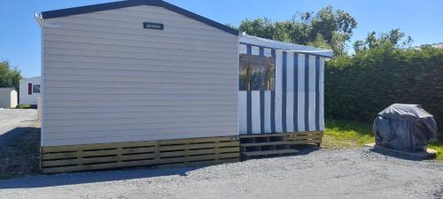 Un pequeño edificio blanco al costado de una carretera. en Mobil-home bord de mer, en Colleville-sur-Mer