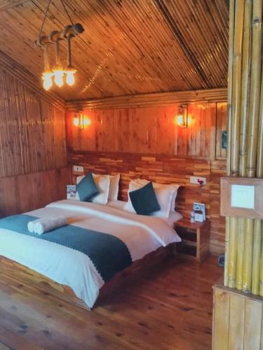 a bedroom with a large bed in a wooden room at THE WONDERLAND COTTAGES & Cafe in Nārkanda