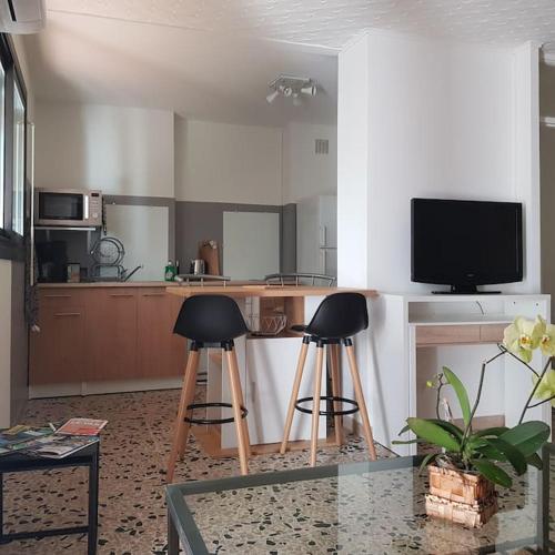 une cuisine avec deux tabourets de bar et une télévision dans l'établissement Studio calme cadre nature à proximité des plages, à La Seyne-sur-Mer
