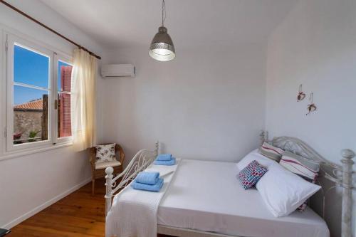 Un dormitorio blanco con una cama y una ventana. en To Patriko Lefkada Cozy Village Home with Parking, en Tsoukaladhes