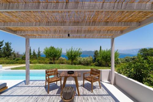 a patio with a table and chairs and a pool at Cavalier Suites Nikiana Lefkada AV Properties in Nikiana