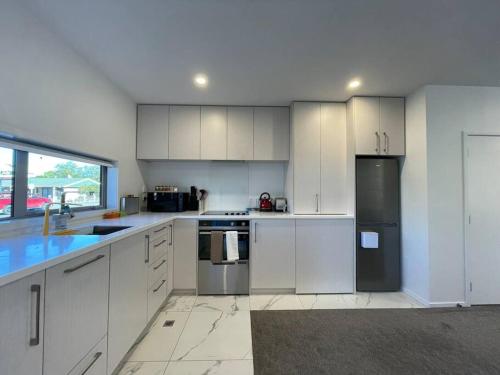 a kitchen with white cabinets and stainless steel appliances at CBD 2 Bedroom Parkside Living By Hagley with Free Parking in Christchurch