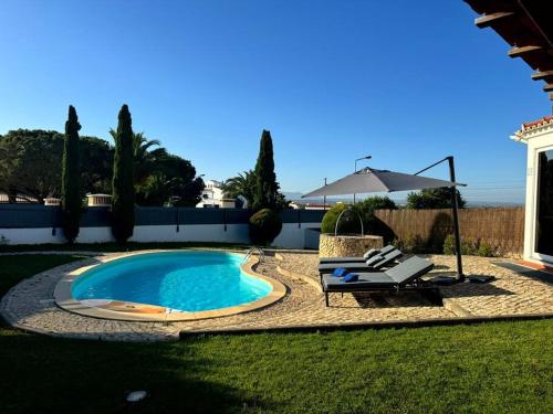 a swimming pool in a yard with a chair and an umbrella at Villa MariSol Ferragudo by Rosado in Ferragudo