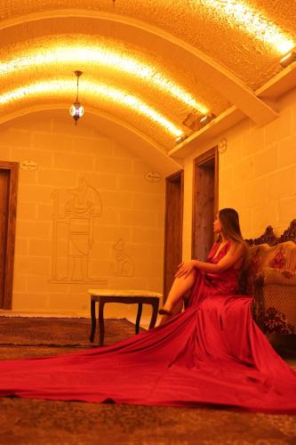 a woman in a red dress sitting on a couch at Ashab-I Kehf Cappadocia House in Nevsehir