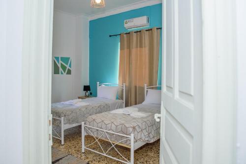 two beds in a room with blue walls at Sotiria's House in Lakkíon