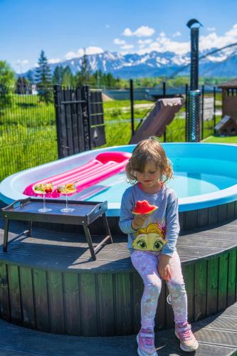 a little girl sitting on a bench next to a pool at GORSKI RESORT Lux Apartments Jacuzzi & Sauna in Poronin