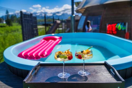 two glasses of food on a tray next to a pool at GORSKI RESORT Lux Apartments Jacuzzi & Sauna in Poronin