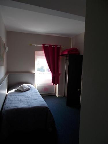 a bedroom with a bed and a window with a red curtain at Hôtel Restaurant La Belle Epoque in Le Creusot