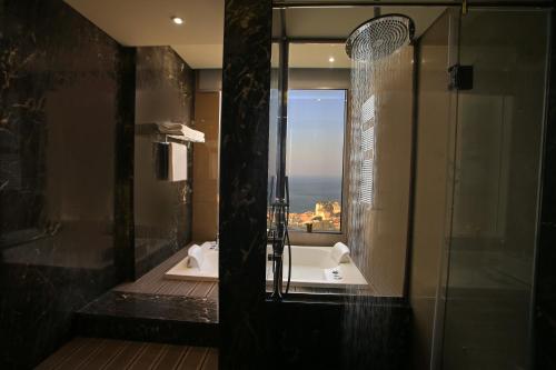 a bathroom with a shower and a tub with a window at Lancaster Plaza Beirut in Beirut