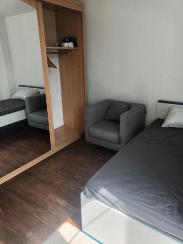 une chambre avec un lit, une chaise et un miroir dans l'établissement Appartement f3, à Cormeilles-en-Parisis
