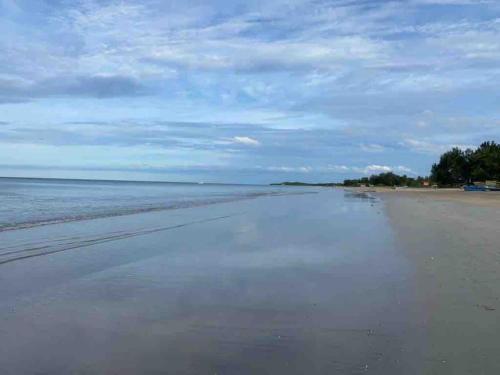 an empty beach with a cloudy sky and the ocean at Sandy Shores in Nilaveli