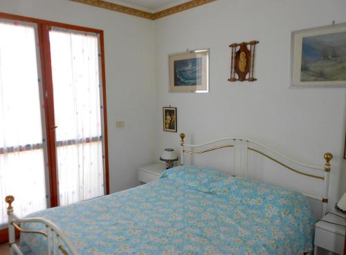 a bedroom with a bed with a blue comforter at Villa Caprera in Rosolina Mare