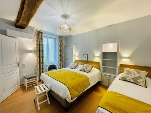 a bedroom with two beds and a yellow blanket at Logis Auberge Du Centre in Chitenay
