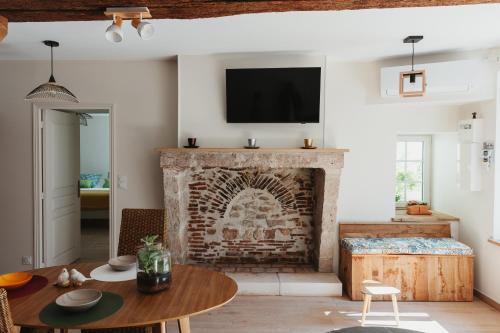 a living room with a brick fireplace with a tv at Logis Auberge Du Centre in Chitenay