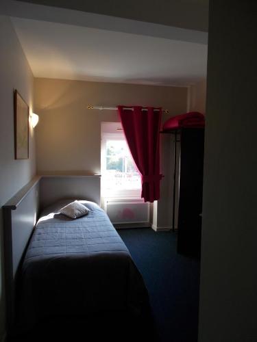a bedroom with a bed and a window with a red curtain at Hôtel Restaurant La Belle Epoque in Le Creusot