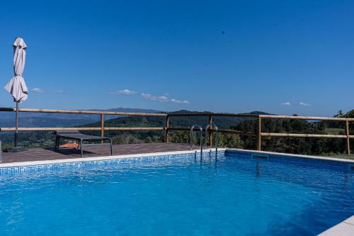 a large swimming pool next to a fence with an umbrella at Casas da Morgadinha - Arais Turismo Rural in Celorico de Basto