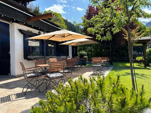 a patio with chairs and tables with umbrellas at Das Halali - dein kleines Hotel an der Zugspitze in Ehrwald