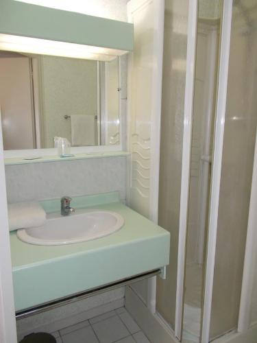 een witte badkamer met een wastafel en een spiegel bij Hôtel Restaurant La Belle Epoque in Le Creusot