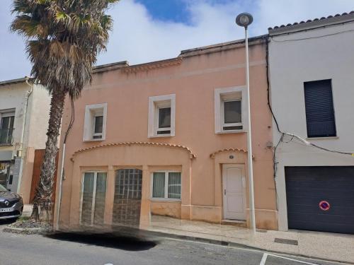 un bâtiment avec un palmier devant dans l'établissement L'Oustal de Provence, à Sète