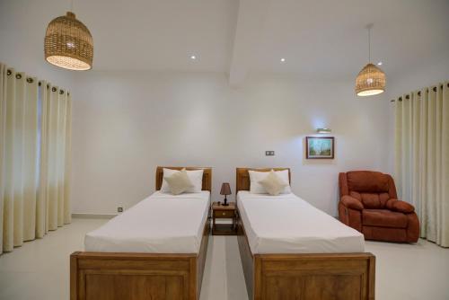 a room with two beds and a chair at Rose Hill Bungalow in Gampola