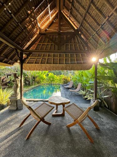 a patio with a table and chairs and a pool at Munay Villa in Ubud