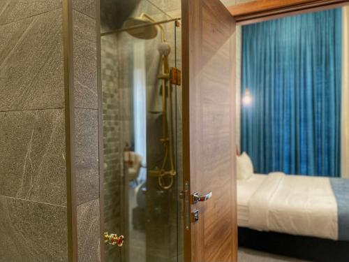 a bathroom with a shower and a door with a bed at Apochi Hotel Tbilisi in Tbilisi City