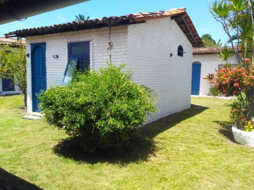 a small white house with a bush in the yard at Pousada Ancora in Vera Cruz de Itaparica