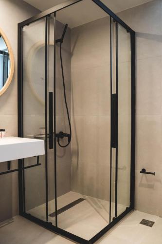 a glass shower in a bathroom with a sink at blue symphony suites and apartments in Nikiana