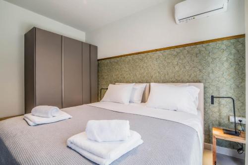 a bedroom with a large white bed with towels on it at blue symphony suites and apartments in Nikiana