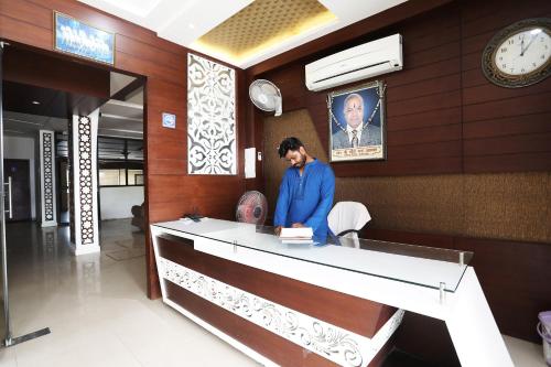 un homme debout à la réception dans un bâtiment dans l'établissement OYO Salt And Pepper Hotel And Resturant, à Nagla Dhīmar