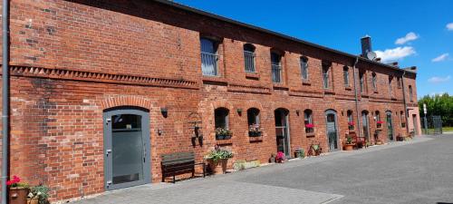 a large red brick building with a door and flowers at Pension Am Dorfanger in Hohennauen