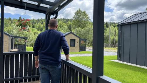 a man standing on a balcony looking out at the yard at Rezort pod Roháčmi in Vitanová