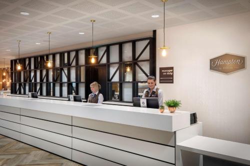 two people sitting at a reception desk at Hampton By Hilton Bristol Airport in Redhill